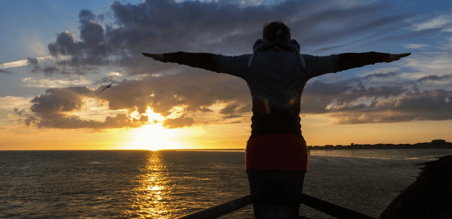 저무는 태양을 보면서 팔을 벌려 심호흡을 하고 있는 모습