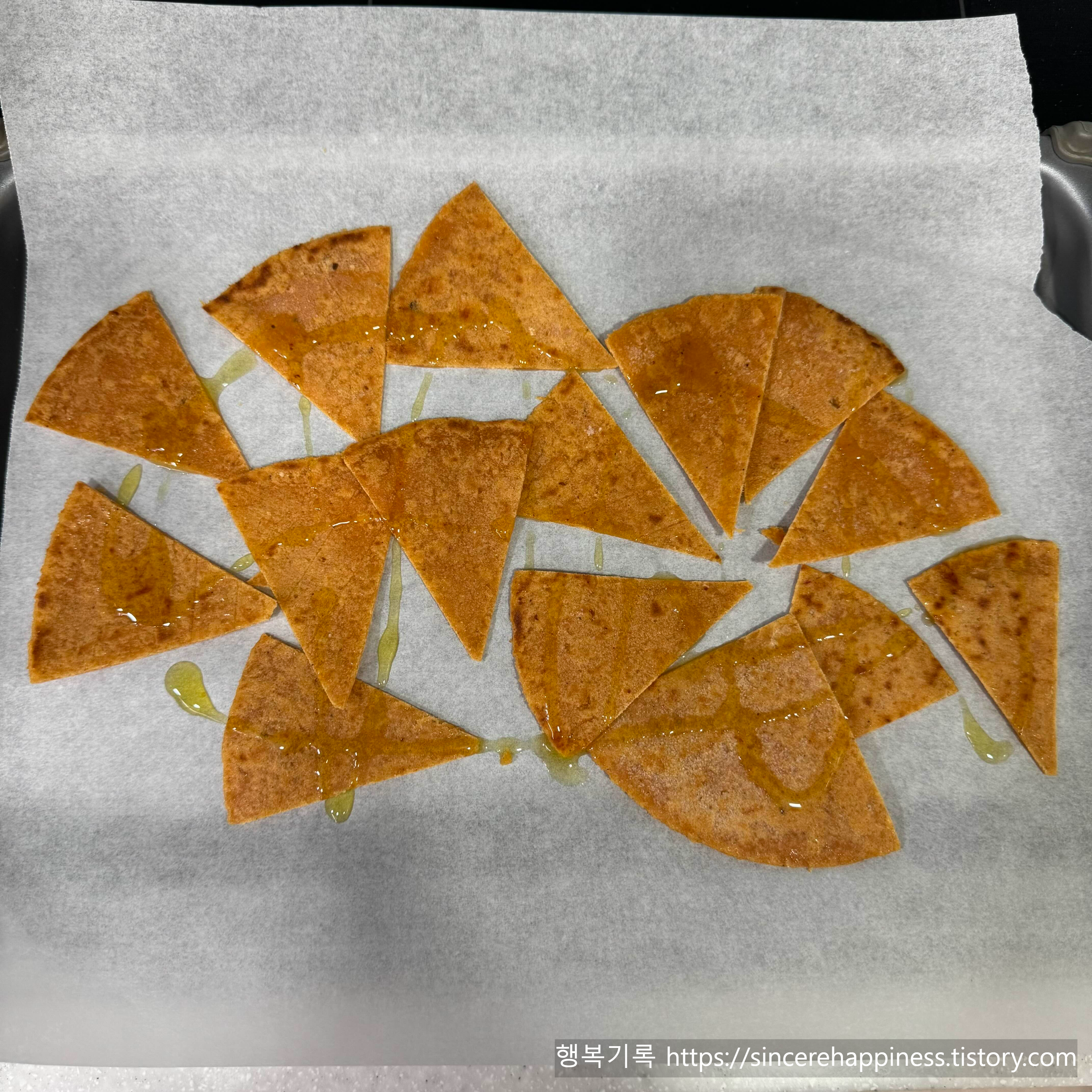 에어프라이어 조리를 위해 자른 또띠아 조각 위에 올리브오일을 흩뿌린 모습