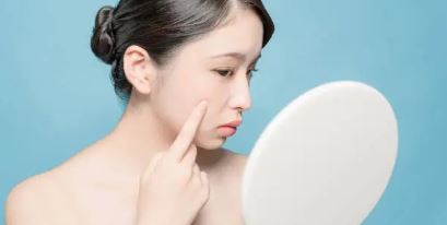 여성이 손거울을들고 뾰루지난부위에 손을 가져다 대고있는 사진