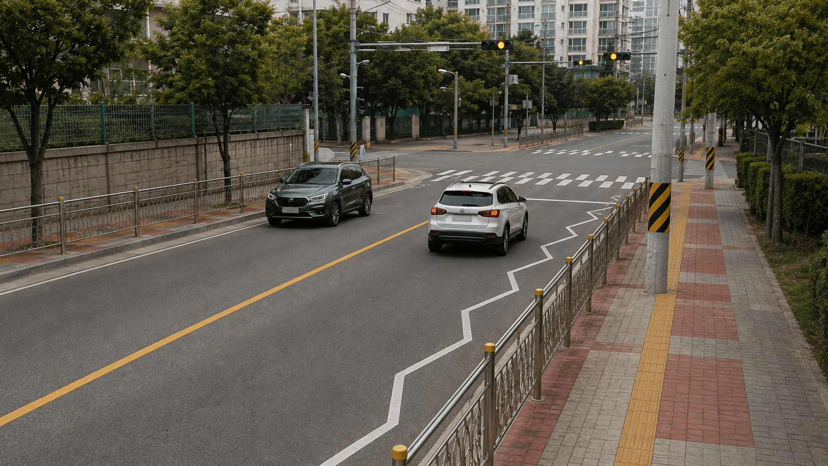 보도 쪽에서 바라본 횡단보도 전방의 흰색 지그재그 서행표시와 주행 차량