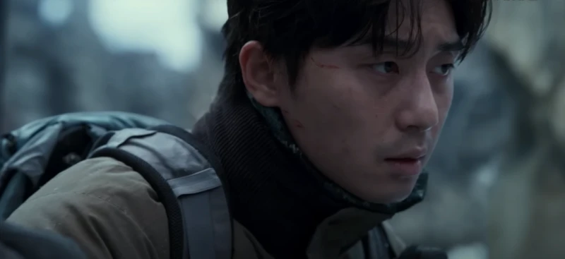 폐허가 된 도시를 배경으로 백팩을 메고 어딘가를 바라보고 있는 박서준