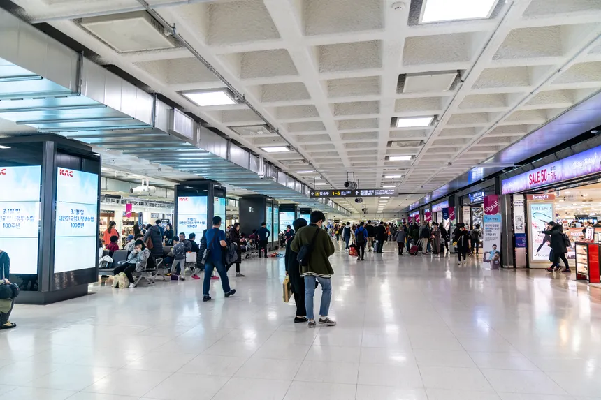 제주공항 탑승 수속 카운터 앞에서 항공편 정보를 확인하는 여행객 모습