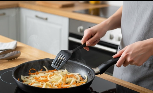 센 불에 양파와 당근을 넣고 주걱으로 재빨리 뒤섞으며 볶아 양파 겉면이 반투명해지도록 익히고 있는 모습