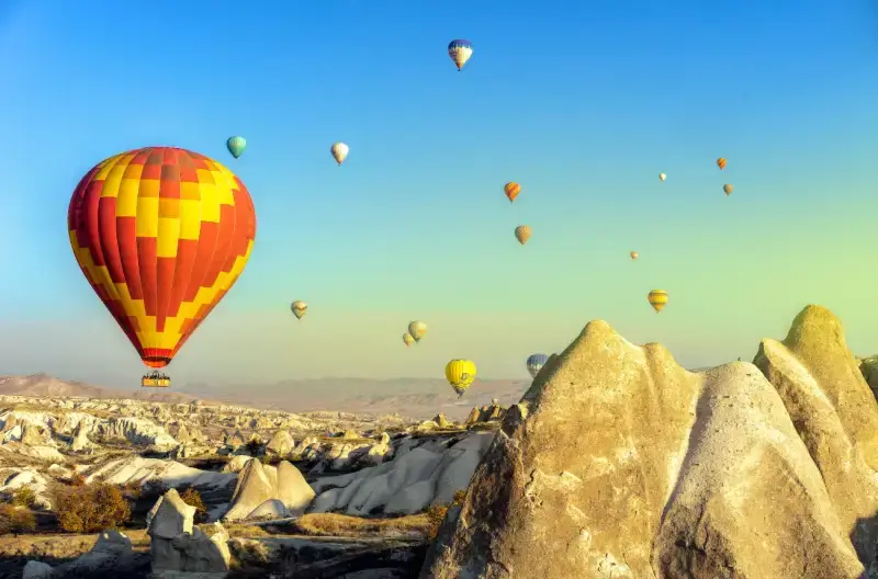 높은-산들과-하늘에-열기구가-떠있는-모습