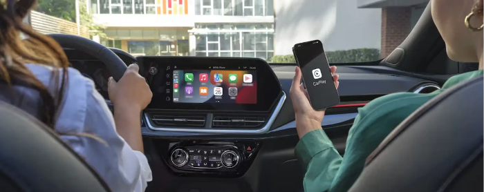 무선 카플레이어를 나타낸 사진. 여자가 운전을 하고 남자가 스마트폰으로 애플 카플레이를 연결한 모습