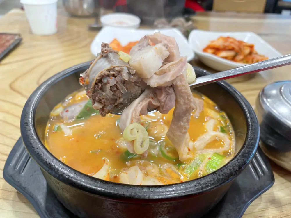 양념장을 풀어 빨간국물이 된 순대국 숟가락으로 순대와 고기를 들어본 모습