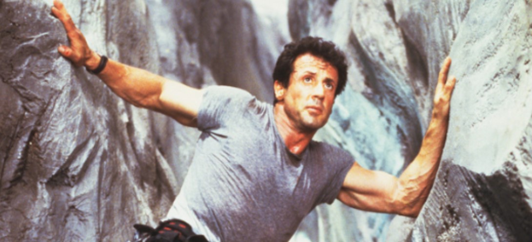 레니 할린 감독의 익스트림 서바이벌 명작 클리프행어(Cliffhanger, 1993)의 한 장면. 실베스터 스탤론(Sylvester Stallone)은 록키와 람보에 이어 90년대 스크린을 장악한 전설적인 구조대원 게이브 워커(Gabe Walker) 역을 맡아, 압도적인 스케일의 고공 액션을 선보였다.