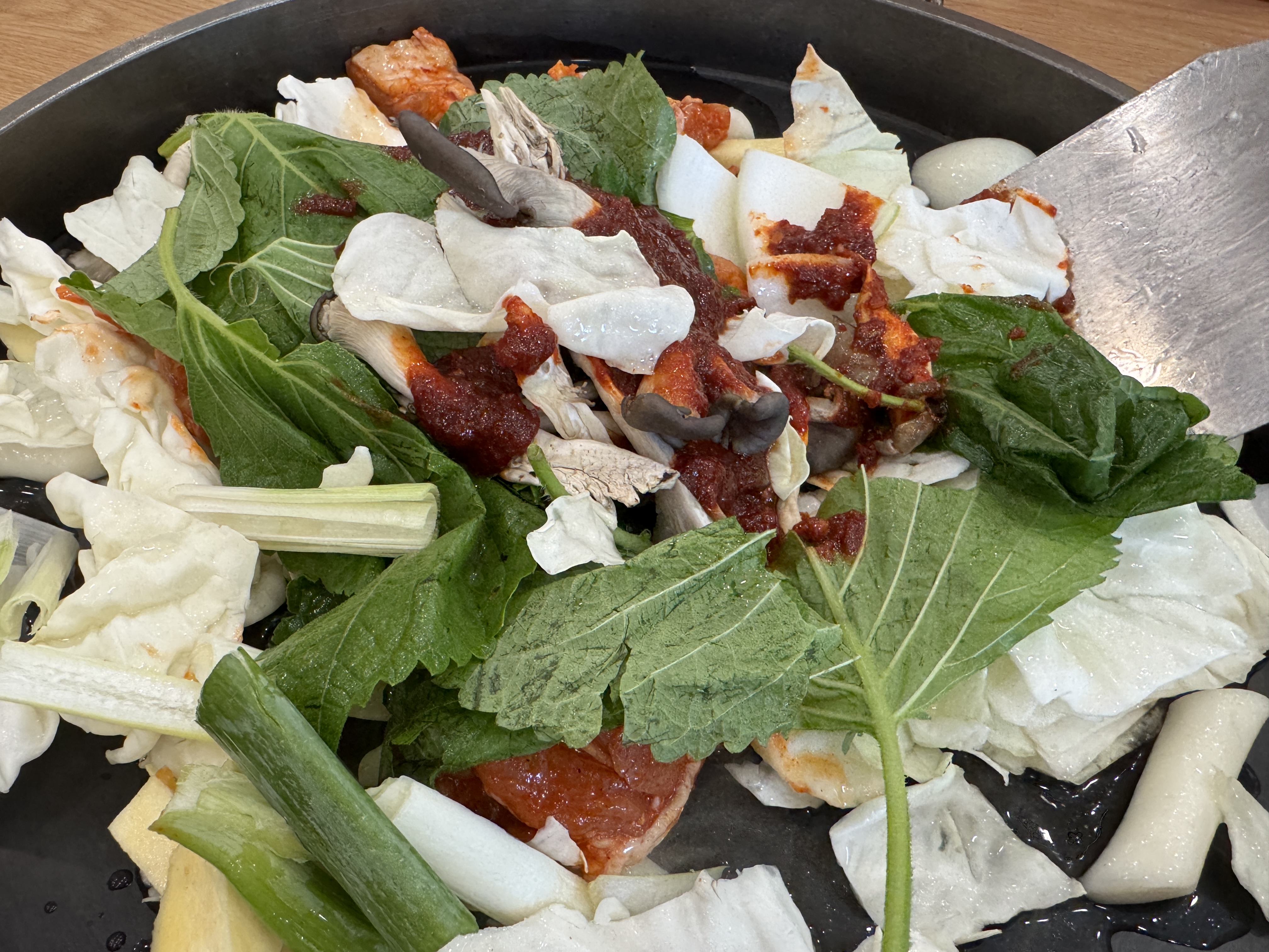 커다란 철판 위에 닭고기&amp;#44; 떡&amp;#44; 양배추&amp;#44; 깻잎&amp;#44; 양파&amp;#44; 대파가 올려진 송정 닭갈비. 빨간 양념이 아직 골고루 섞이기 전 상태. 