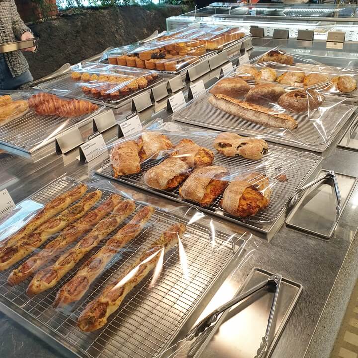 인포메이션카페에서-다양한-빵들을-판매하고-있는데-기다란-소세지가-들어가있는-소세지페스트리와-시그니처메뉴인-토마토치즈치아바타-올리브치즈치아바타-바게트와-깜빠뉴와-같은-제빵류를-팔고-있다
