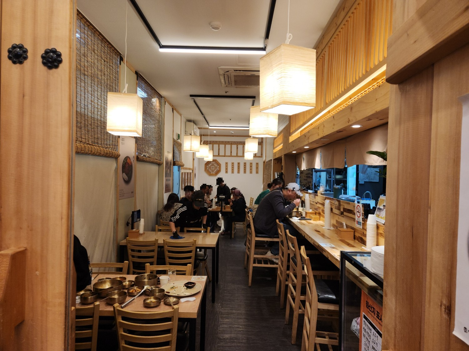 식당 안에 테이블과 의자가 있고 사람들이 앉아 식사를 하고 있는 모습