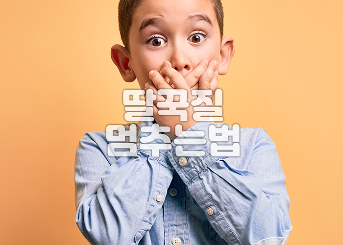 소년이 딸국질을 한후 놀라서 양손으로 입을 막고 있다