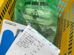 노란색 장바구니아 안에 봉투가 있고, 카드 영수증이 함께 있는 사진입니다.