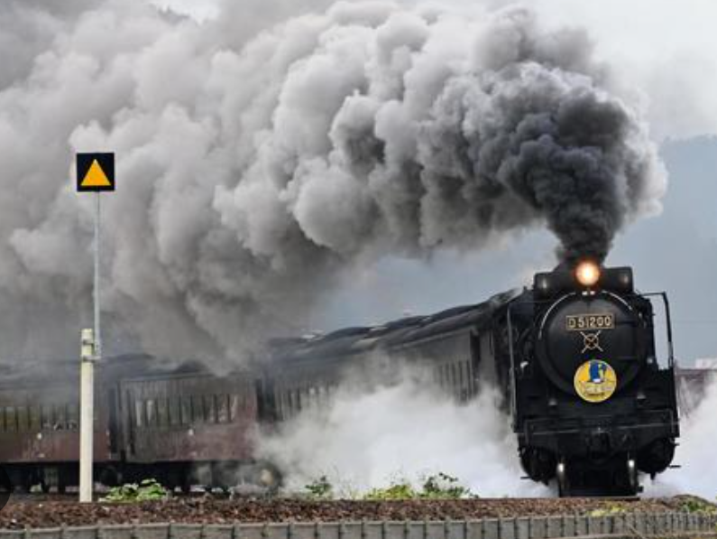 검정색 옛날기차가 연기를 날리면 달리는 모습