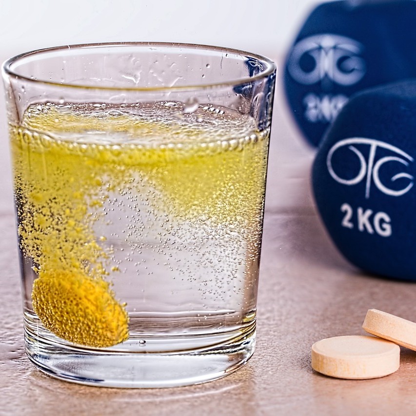 벤포티아민(Benfotiamine)이 에너지생성에 도움이 되는 것을 표현하기 위한 물속에 넣은 비타민b 테블렛과 아령 사진