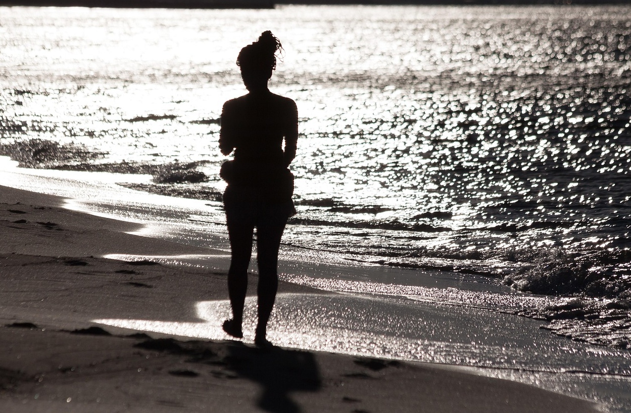 해질 무렵 한 여성이 해변을 걷고 있다