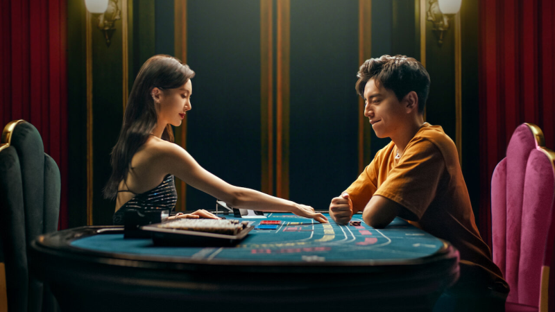 영화 고추일척 스틸컷, 캄보디아 납치 사건을 배경으로 카지노 테이블에서 마주한 남녀 등장 인물