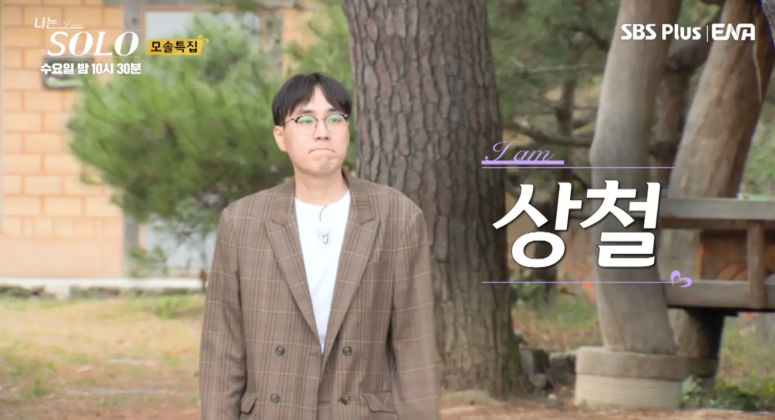 솔로- 갈색 쟈켓 흰색 면티릉 안에 입고 검을 뿔테 안경을 쓴채 나무들이 있는 길을 걷는 상철