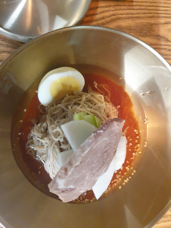 계란, 파, 무, 고기 고명이 올라가있는 빨간 양념의 비빔냉면