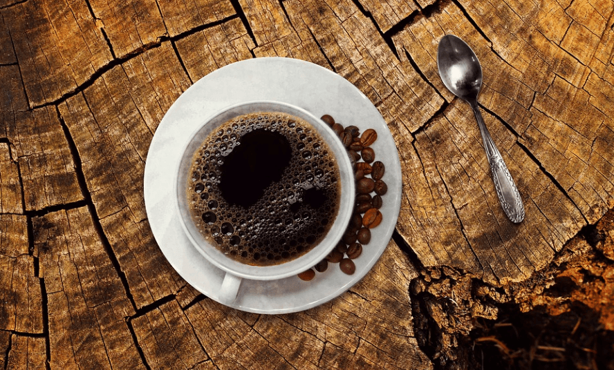 커피콩과 커피가 커피 잔 위에 함께 놓여 있다