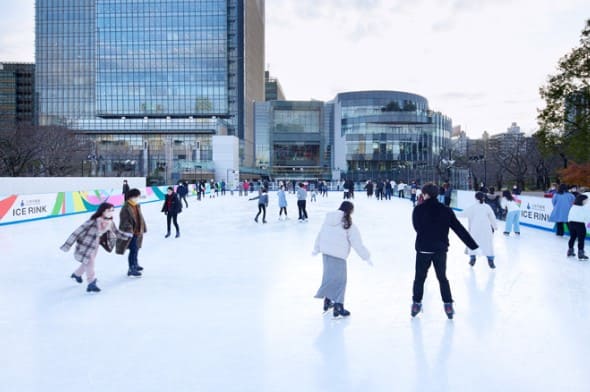 아이스링크위에 스케이트를 신은 사람들이 서 있다.