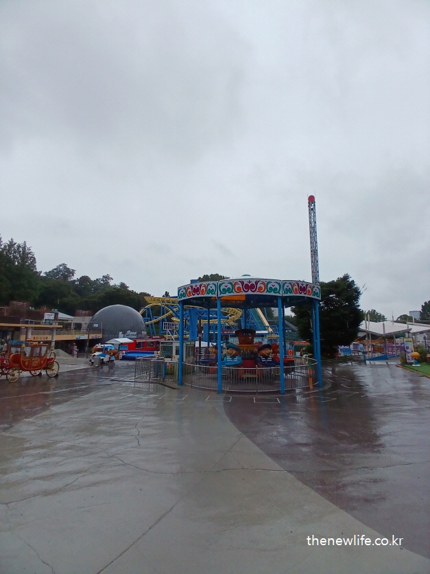 Carousel ride and surrounding attractions in the Children’s Grand Park on a rainy day./비 오는 날 서울 어린이대공원의 회전목마와 주변 놀이기구 모습.