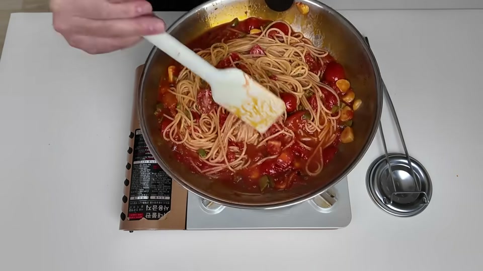 면과 토마토 소스를 함께 섞는 장면