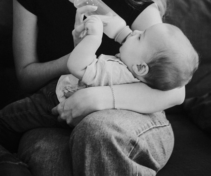 아기에게 젖병으로 분유를 먹이고 있다.