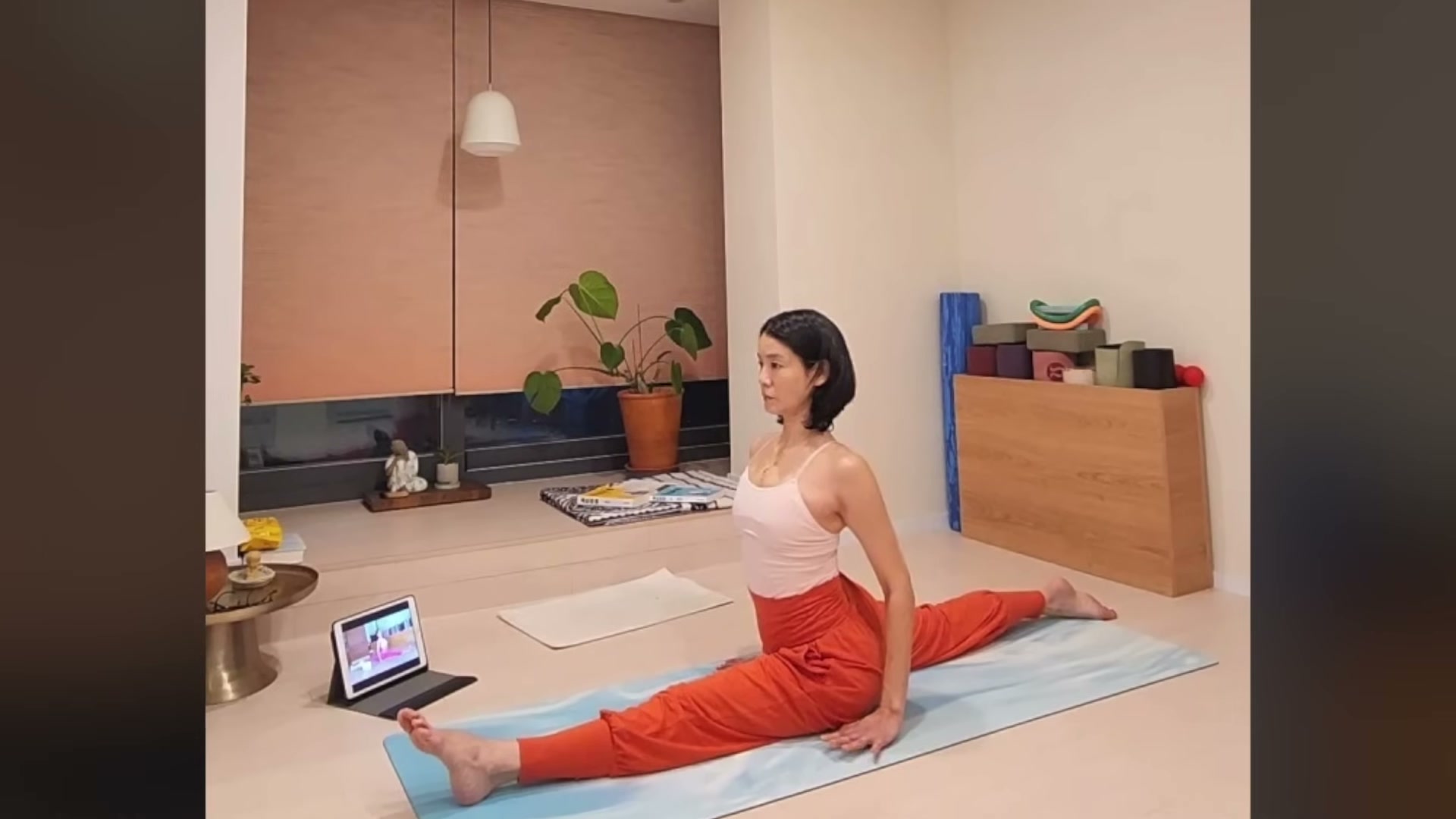 주황색 요가 팬츠를 입은 김지호가 자택 매트 위에서 다리를 일자로 완전히 찢은 자세로 앉아 있는 모습