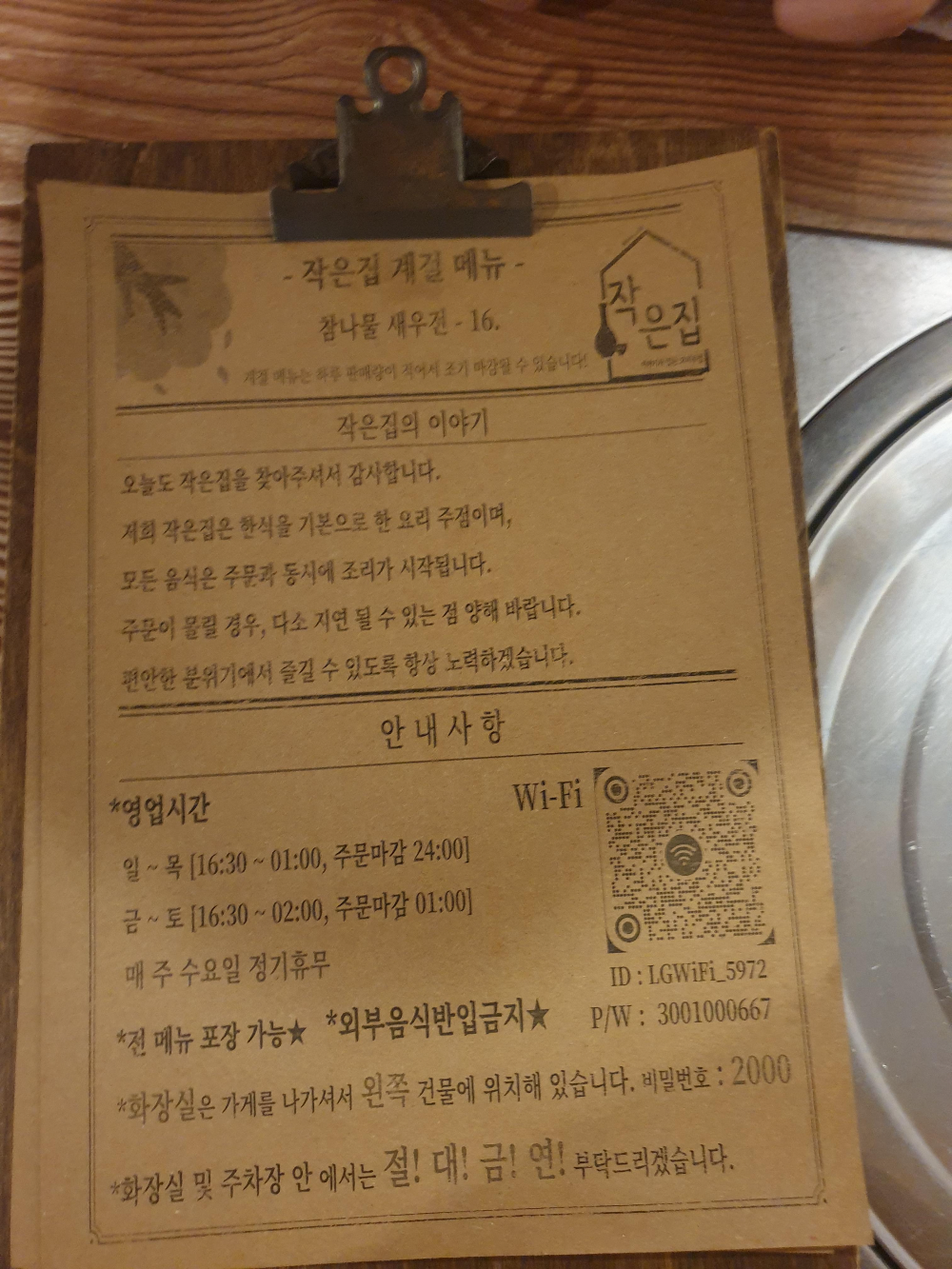 테이블 위에 집게로 묶여있는 메뉴판. 황색 거친 용지에 검은 글씨로 메뉴가 써있다.