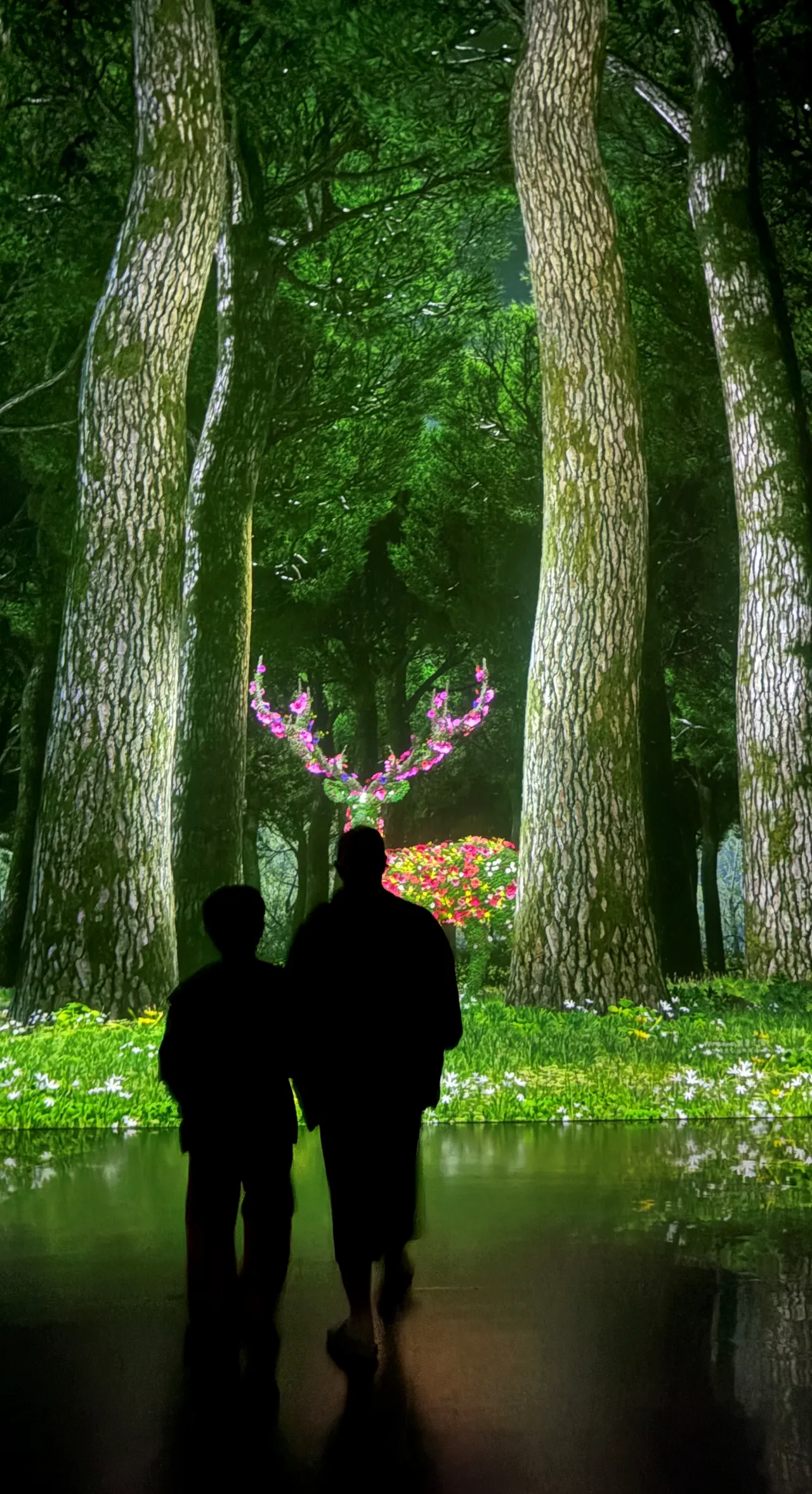 a꽃사슴-미디어-전시-앞에 어른과-아이-구경하는-뒷모습-그림자