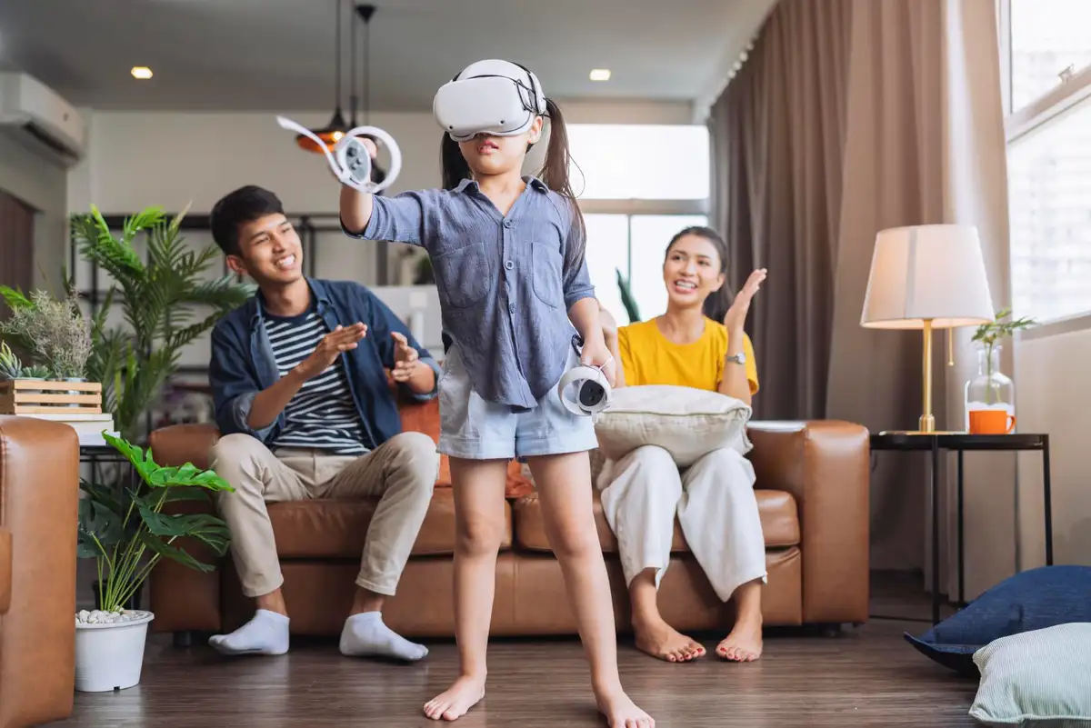 Exiting daugther wear vr headset playing virtual gaming sport innovation while her parent sit and cheering together on sofa counh living room at homeasian family spending fun moment weekend activity.