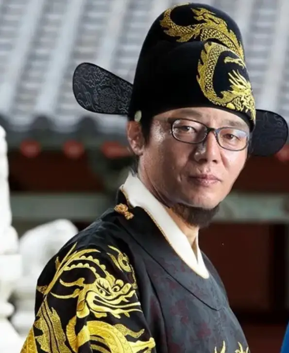 황선홍- 궁궐이미지 앞 검은 조선왕의 모자자 옷을입고 옆으로 비스듬히 선채 앞을 바라보고 있는 황선홍 감독