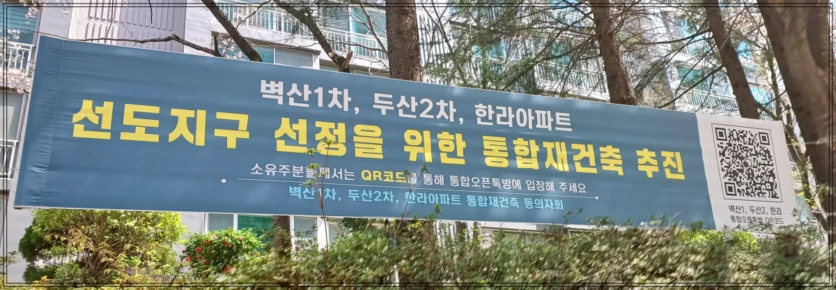 벽산1차-두산2차-한라아파트-선도지구-선정을-위한-통합재건축-추진이라는-현수막-통합오픈톡방에-들어갈-수-있는-QR코드도-있음-뒤에-아파트배경