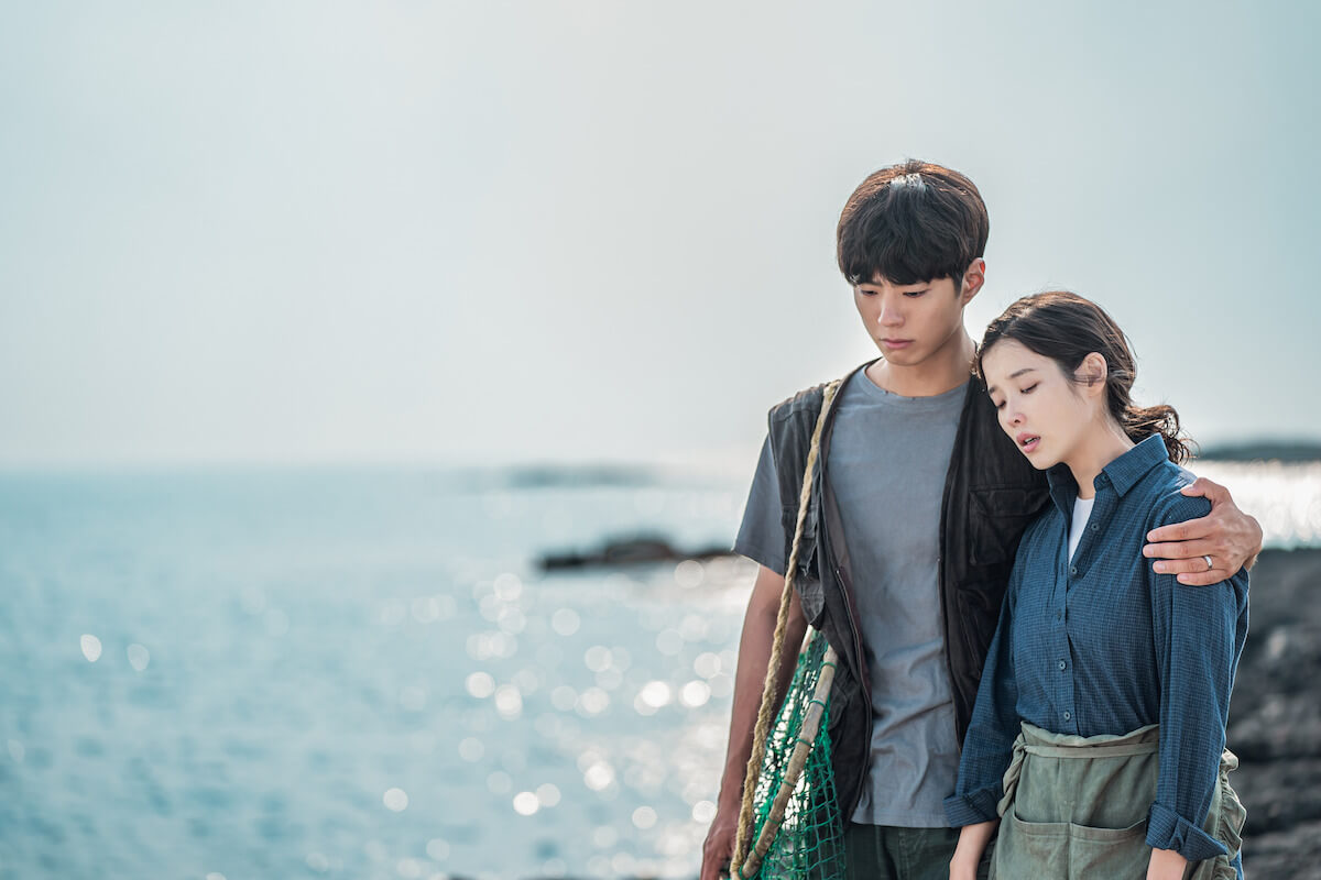 When Life Gives You Tangerines에서 아이유(애순 역)와 박보검(관식 역)이 제주 바닷가를 배경으로 의지하는 포즈로 한 컷