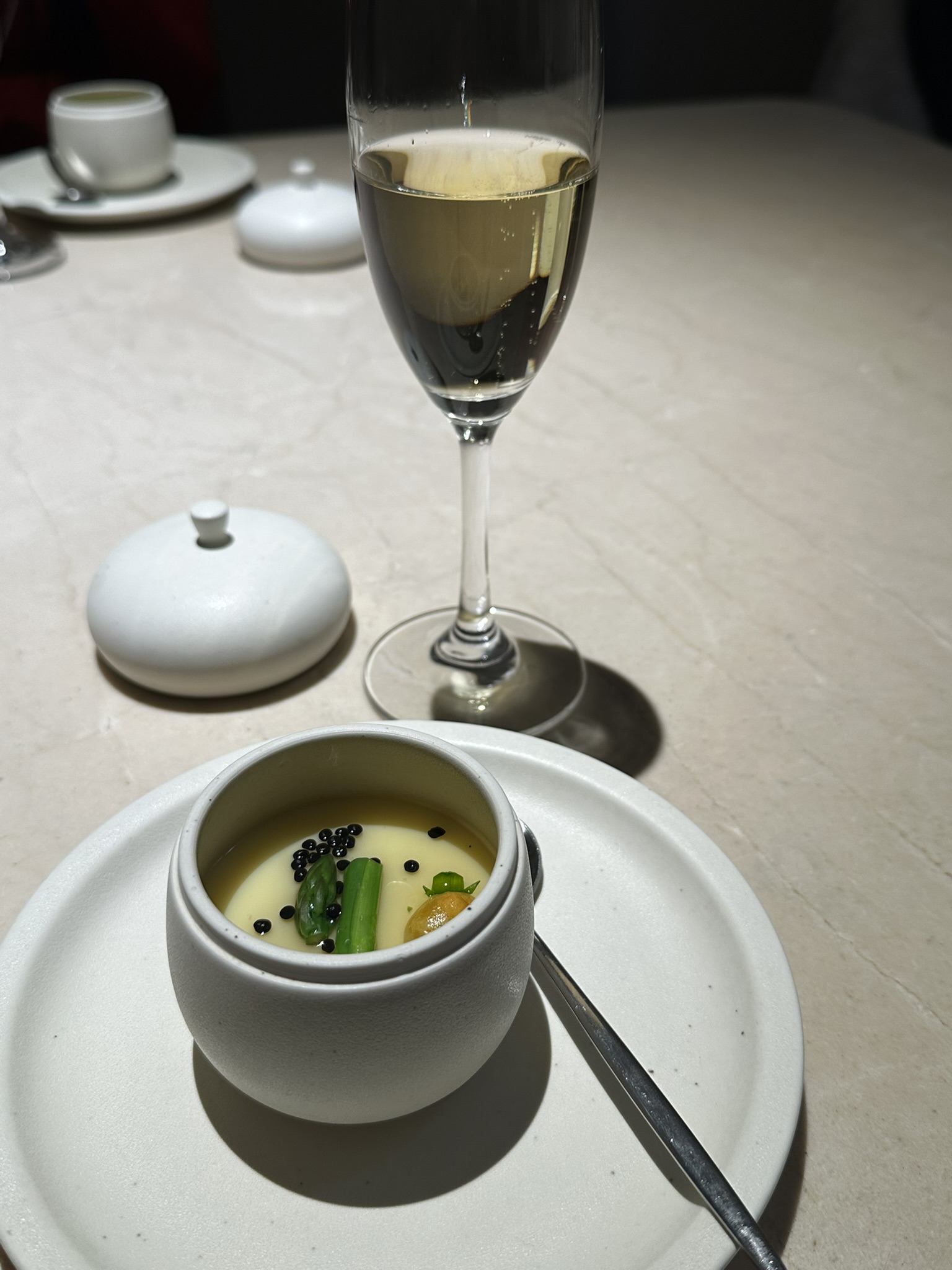 정갈한 접시에 놓인 차완무시와 스파클링 와인 1잔이 있는 사진