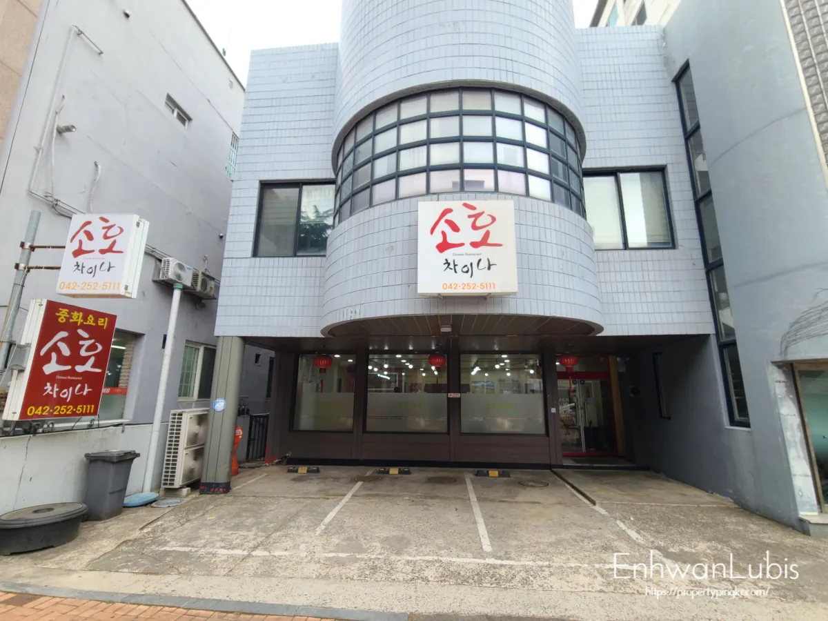 회색건물-가운데-동그랗게-튀어나온-하얀색-간판이-걸려있다.