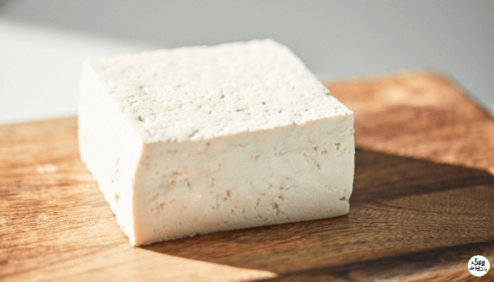 나무도마 위에 흰 두부한모가 놓여져 있다