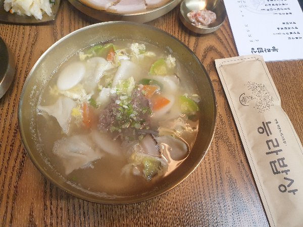 떡과 만두가 함께 있는 만둣국. 위에는 파와 고기 고명이 올려져 있다.