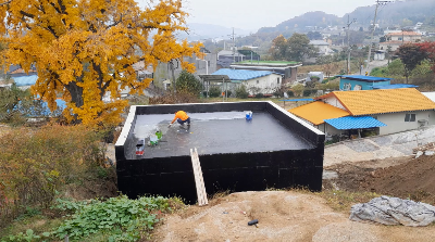 옥상에서 방수 페인트를 칠하고 있는 인부