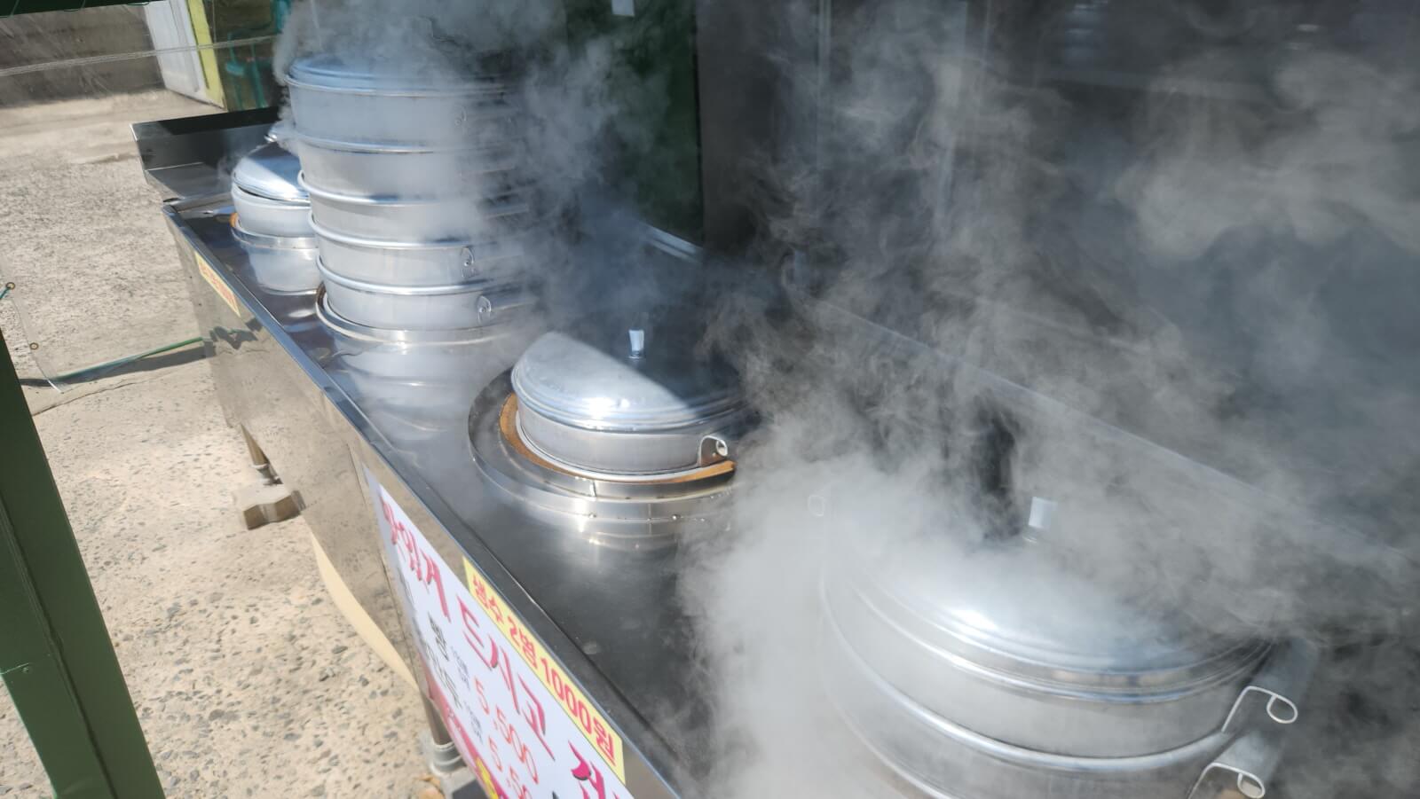 김이 모락모락 나는 스테인리스 찜기에서 찐빵과 만두를 찌는 모습