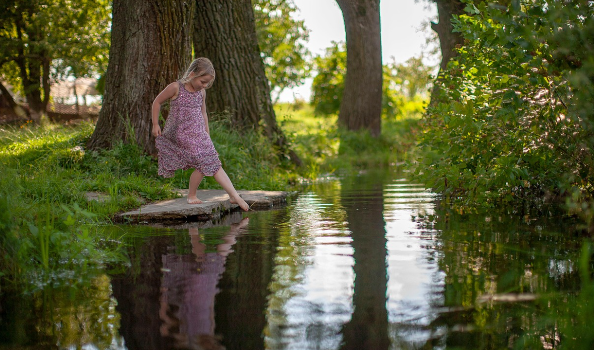호수에 발을 담그는 어린 여자 아이
