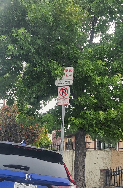 푸른 나무 아래 LA 주택가 도로변에 설치된 여러 개의 주차 표지판 이미지