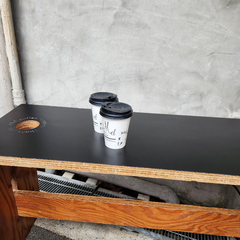 검은색으로 칠해진 의자 위 커피 두 잔이 올려져 있다.