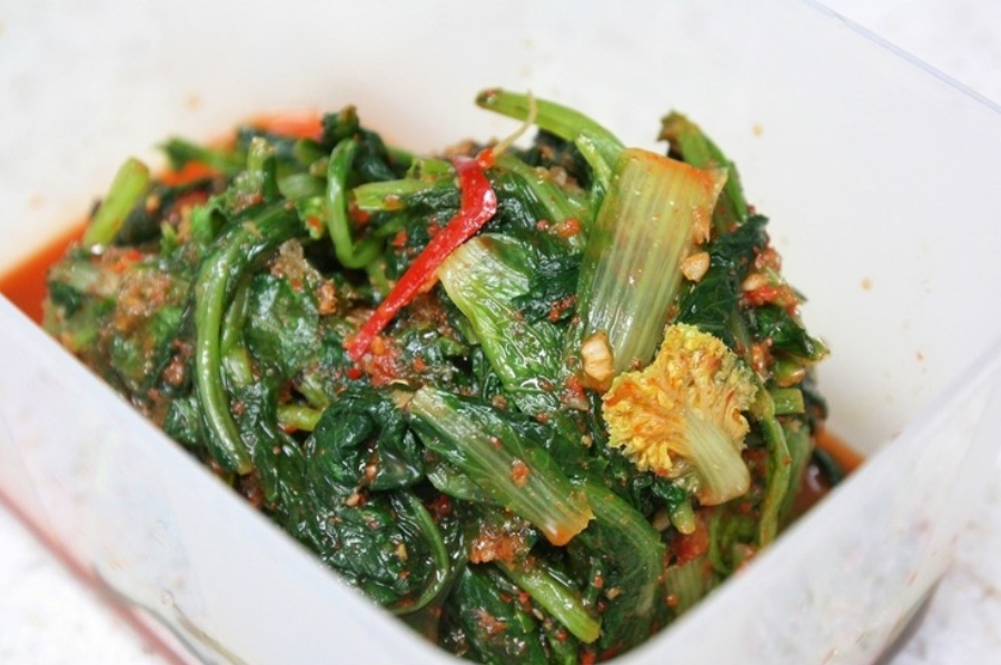 야생에서 채취를 한 열무의 줄기를 잘 세척하고 다듬어서 각종 양념을 넣고 버무린 열무김치를 네모난 그릇에 반쯤 담아두고 찍은 사진