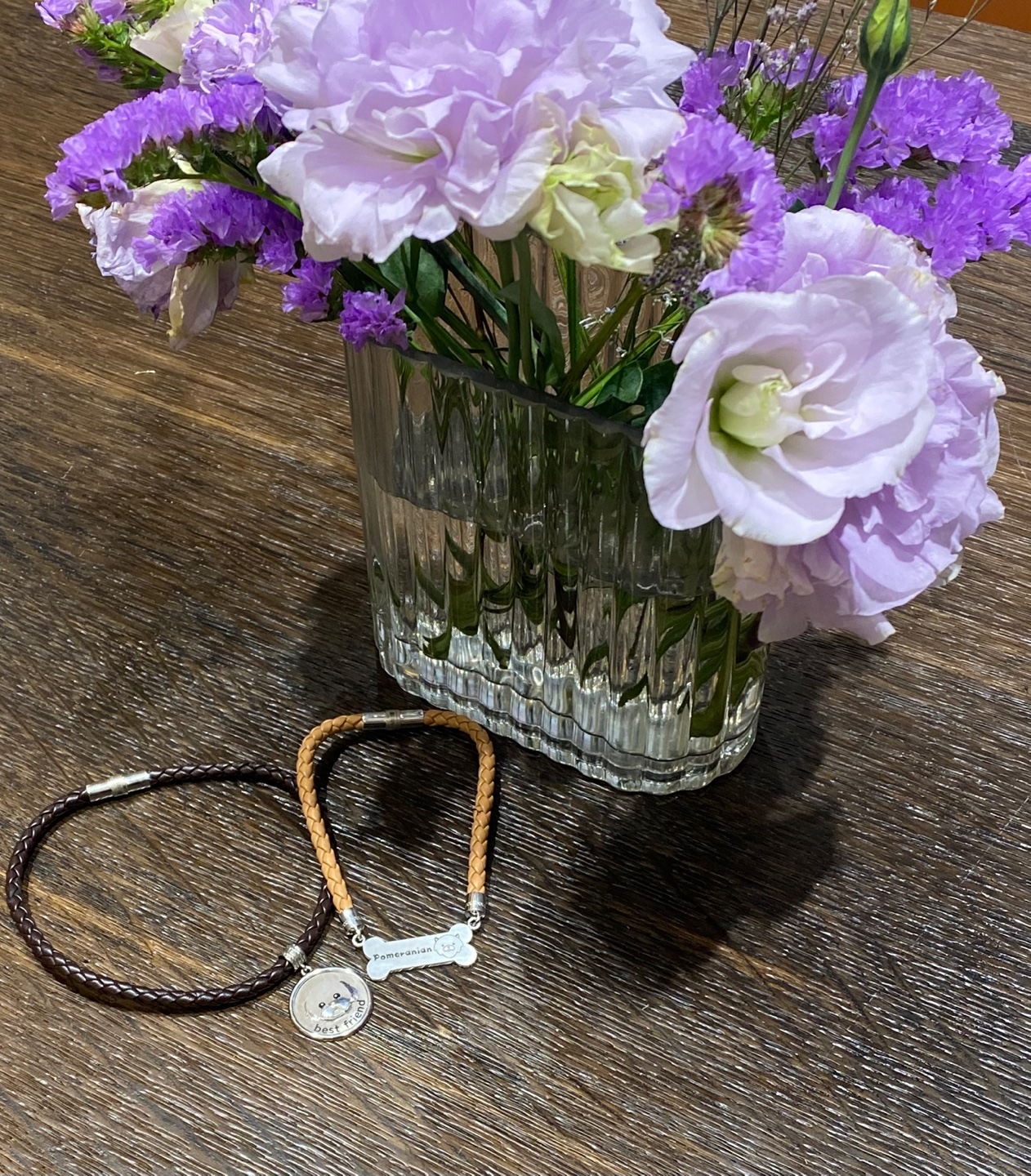 강아지 목걸이 두 개가 꽃 밑에 전시되어 있는 사진입니다.