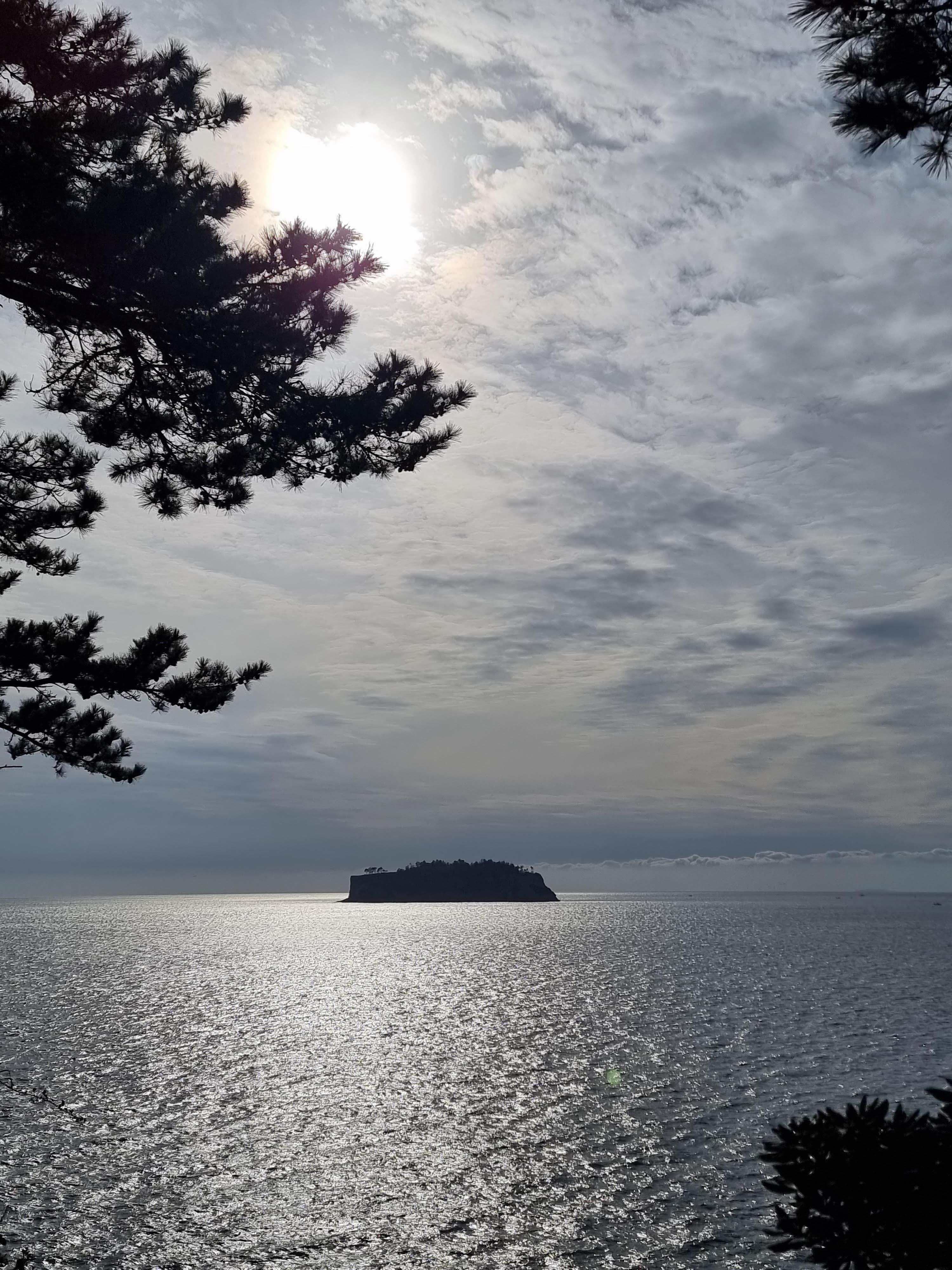 외돌개주변의 석양빛 바다와 멀리 보이는 섬