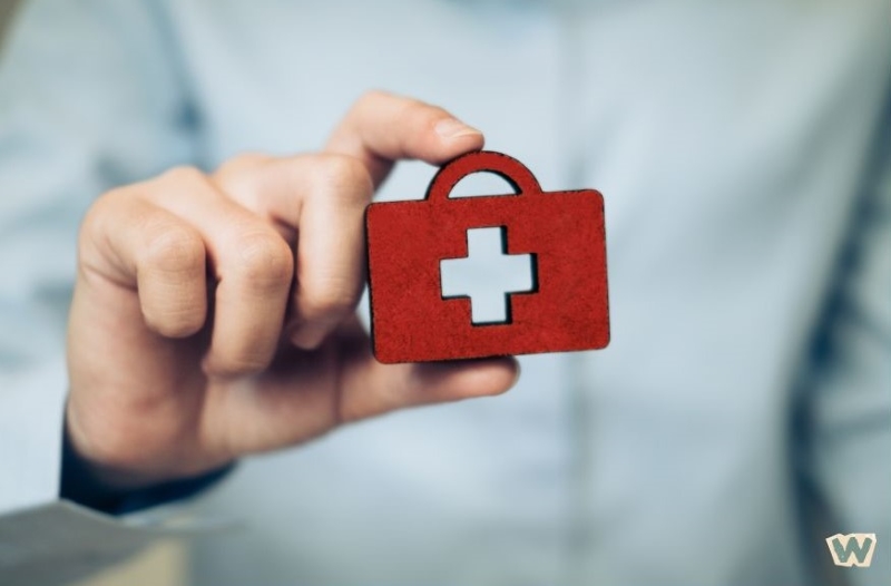 의료 십자가 마크가 있는 빨간 의료가방을 들고 있는 손 - 건강보험 보장 및 의료비 보험금 지급 개념 via canva