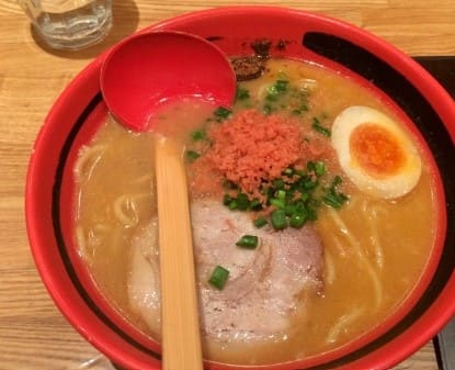 빨간 그릇에 갈색 국물과 면발이 보인다