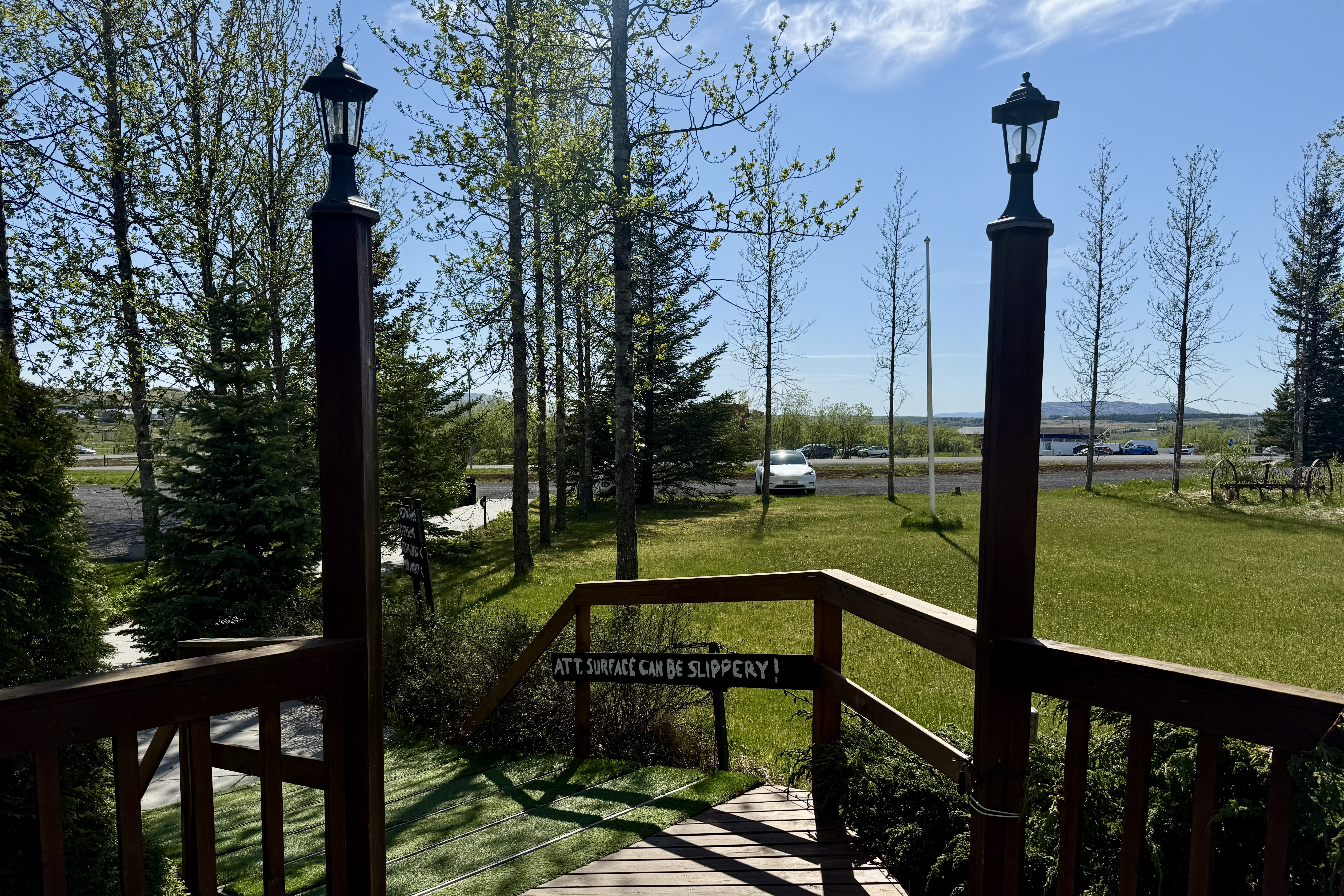 야외에서 본 블루호텔 진입 계단과 잔디, 그리고 "ATT. SURFACE CAN BE SLIPPERY!"라는 경고 문구가 적힌 안내판