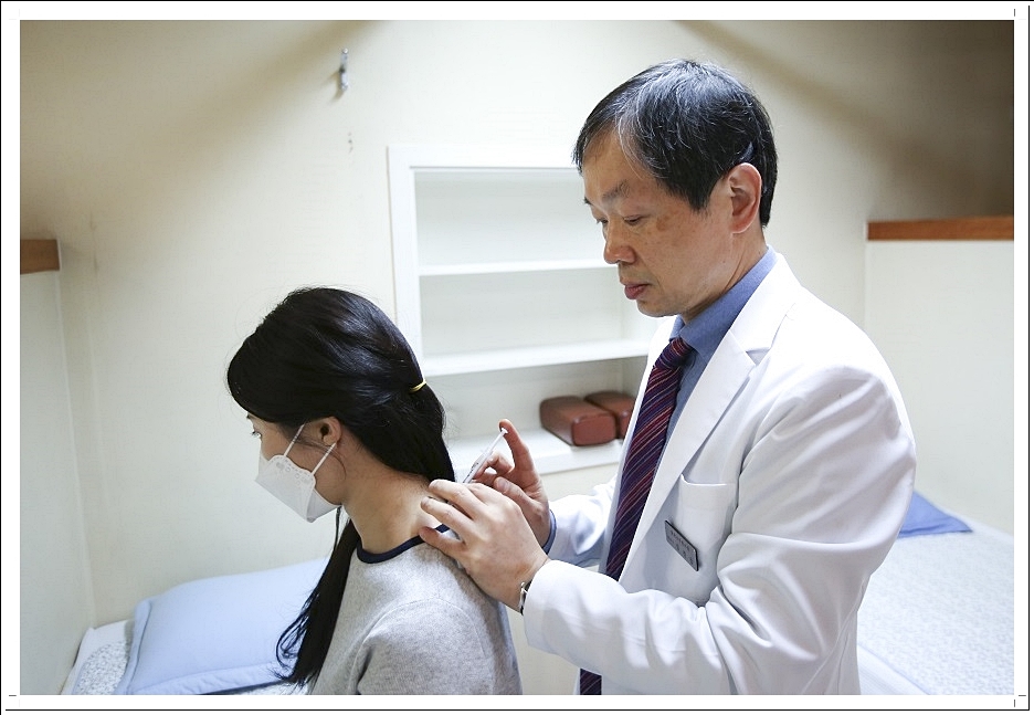 환자의 목뒤에 약침을 놓고 있는 한의사의 모습